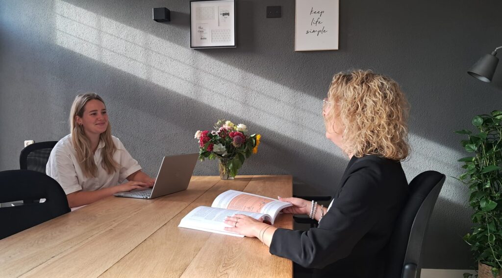 Twee mensen in gesprek aan een houten tafel
